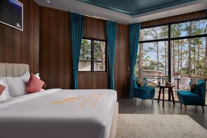 Une chambre d’hôtel moderne avec un grand lit, des rideaux de couleur turquoise et un balcon doté d’un espace salon extérieur.