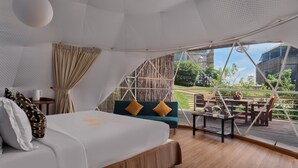 A spacious room with a large bed, a wooden table, and a view of the outdoors.