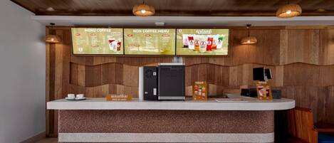A coffee station with a menu board, a coffee machine, and a counter.