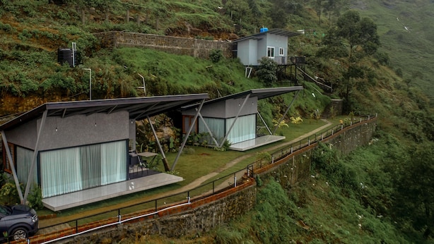 A modern hillside property with two main structures, one with a flat roof and the other elevated on stilts. - Noah Crest (Kodaikanal)