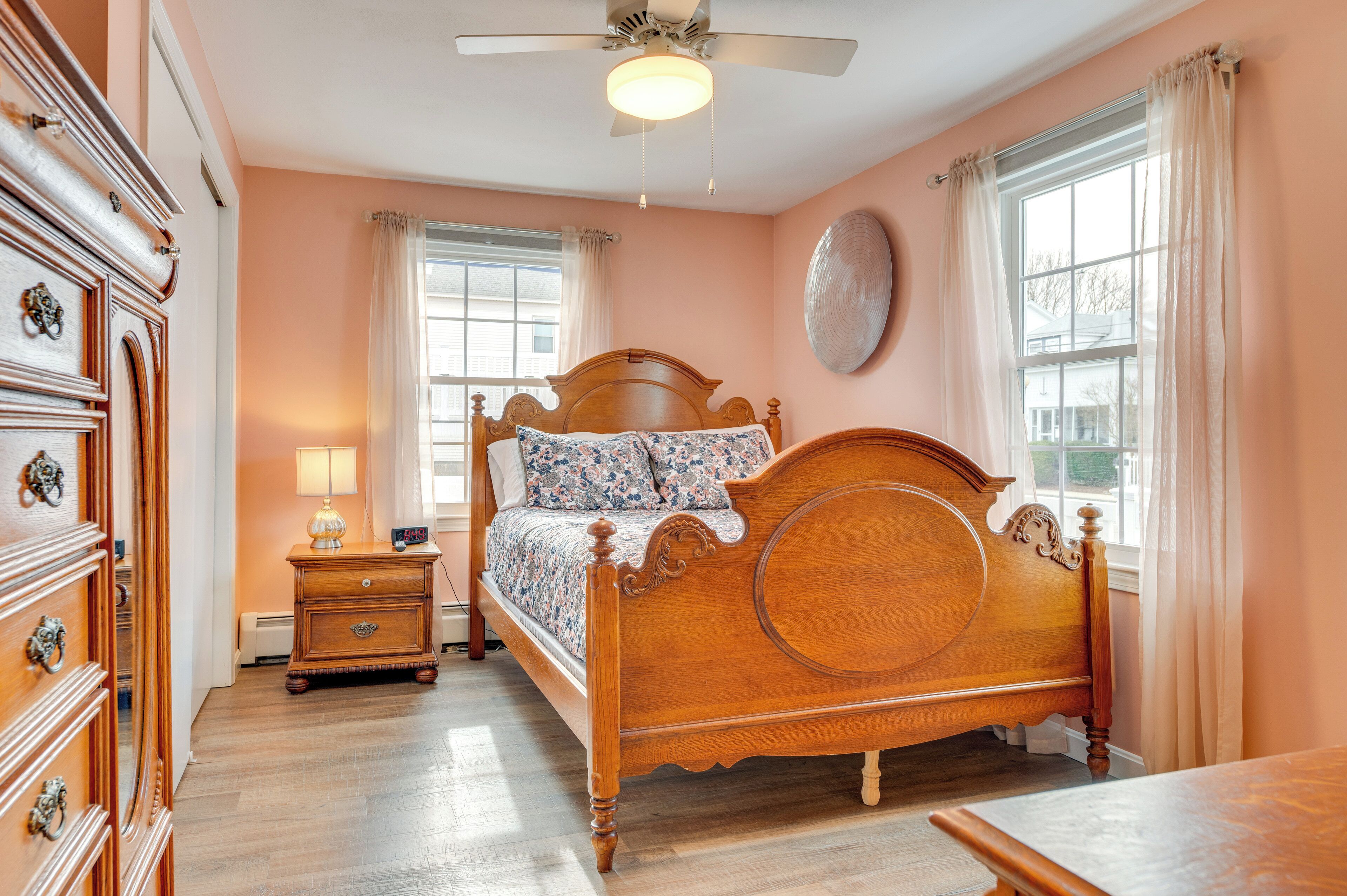 A bedroom with a wooden bed, a nightstand, a dresser, and a ceiling fan.