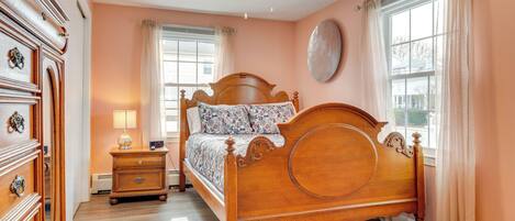 A bedroom with a wooden bed, a nightstand, a dresser, and a ceiling fan.