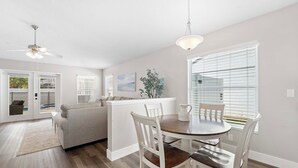 A modern kitchen with white cabinetry, a dining area with a round table and white chairs, and a ceiling fan. - Saltwater Pool & Spa at Home in Bradenton (Bradenton)