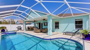 A swimming pool with a covered patio area, outdoor furniture, and a clear blue sky. - Saltwater Pool & Spa at Home in Bradenton (Bradenton)
