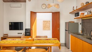 Uma cozinha moderna com micro-ondas embutido, geladeira e uma mesa de jantar de madeira com cadeiras.