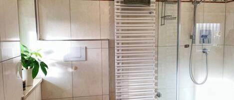Un baño con inodoro, ducha y toallero.