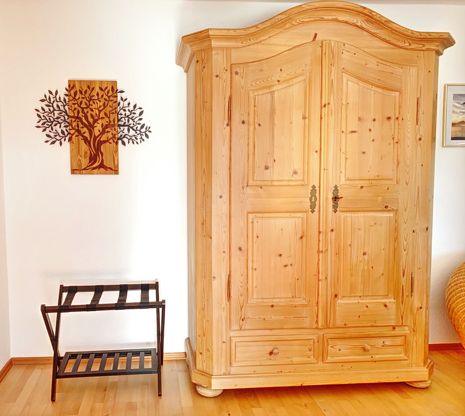 A wooden wardrobe with two doors and a bench in front.