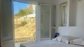 A bedroom with a large bed, a window, and a door leading to an outdoor area.