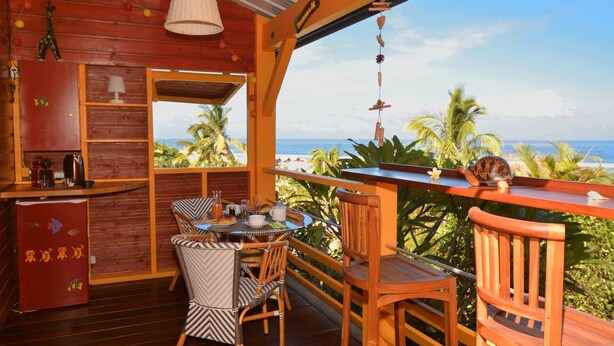 A wooden interior with a balcony overlooking a beach. - Direct Privilege Rate - 2 adults (Saint-Paul)