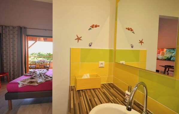 Habitación de hotel con cama, baño con lavamanos y espejo, y ventana con cortinas.