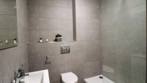 A modern bathroom with a bathtub, toilet, and sink. - Charming 2-Bed Apartment in Dublin's Countryside (Ballyboughal)