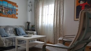 Un salon avec un canapé, une table basse, un fauteuil et un tableau accroché au mur.