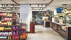 Una tienda minorista moderna con pasillos de aperitivos, una cafetería y un mural.