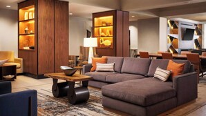 A modern living room with a sectional sofa, wooden shelving units, and a dining area with a table and chairs.