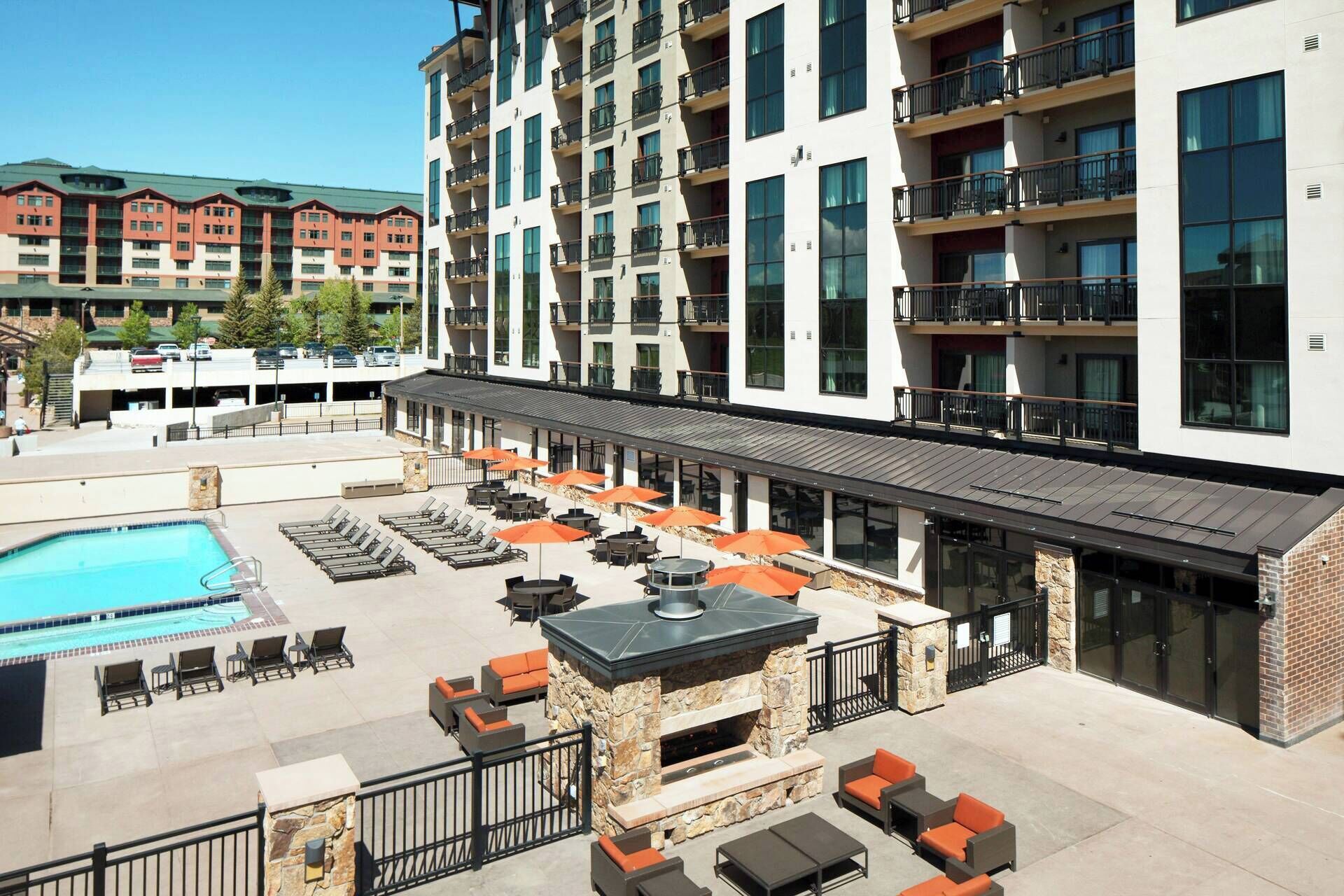 A rooftop pool area with lounge chairs and a stone fireplace.