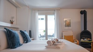 Una camera d'albergo con un letto, una TV, un camino e un balcone con sedute all'aperto.