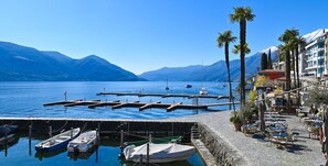 Un port de plaisance avec des bateaux amarrés, un chemin pavé et des bâtiments dotés de balcons donnant sur l’eau.