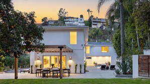 A modern two-story house with a patio area featuring outdoor furniture and a pool. - Hollywood Hills Retreat • Pool + Spa + Outdoor Dining + Views | Skyline Chalet (Los Angeles)
