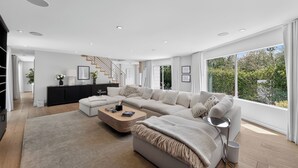 A modern living room with a sectional sofa, a coffee table, and a staircase leading to another level. - Hollywood Hills Retreat • Pool + Spa + Outdoor Dining + Views | Skyline Chalet (Los Angeles)