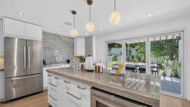 A modern kitchen with stainless steel appliances, a granite countertop, and a view of an outdoor patio. - Hollywood Hills Retreat • Pool + Spa + Outdoor Dining + Views | Skyline Chalet (Los Angeles)