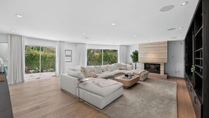 A modern living room with a sectional sofa, a coffee table, and a fireplace. - Hollywood Hills Retreat • Pool + Spa + Outdoor Dining + Views | Skyline Chalet (Los Angeles)