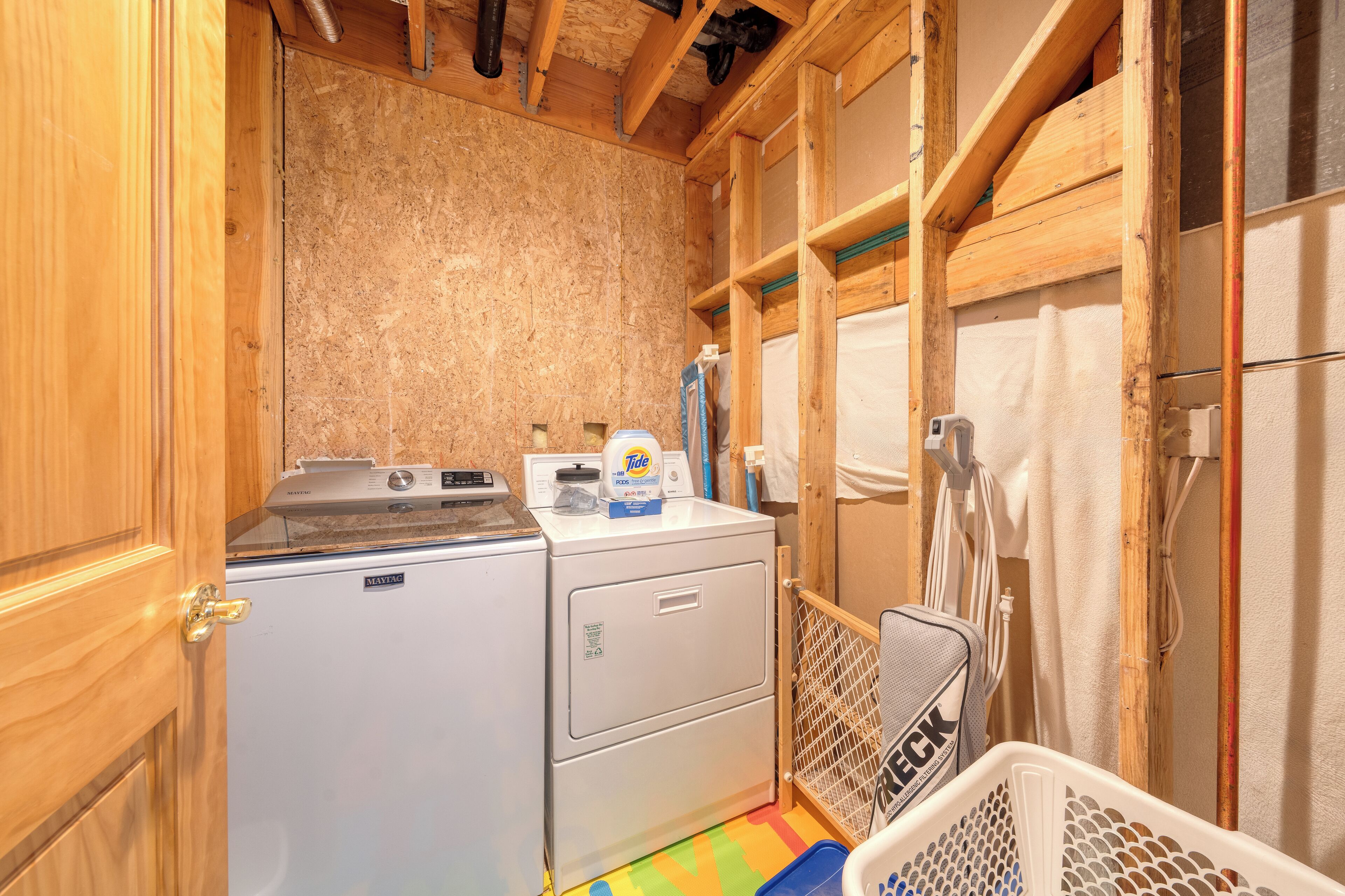 Une petite buanderie comprenant un lave-linge, un sèche-linge et une petite table à repasser.
