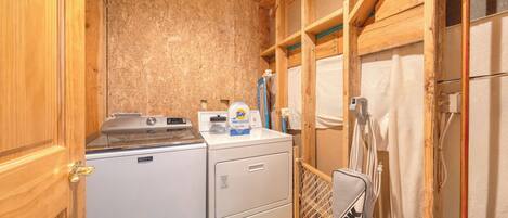 Une petite buanderie comprenant un lave-linge, un sèche-linge et une petite table à repasser.
