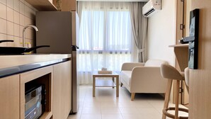 A modern kitchen with a built-in oven, a stove, and a refrigerator. There is a dining area with a sofa and a small table. - Fantasea Condo Kamala (Kamala)
