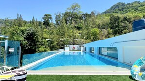A clear blue swimming pool with a view of a forested hillside. - Fantasea Condo Kamala (Kamala)