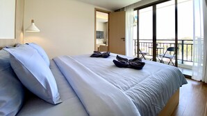 A modern hotel room with a large bed, a ceiling light, and a balcony with chairs. - Fantasea Condo Kamala (Kamala)