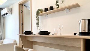 A modern kitchen with a wooden countertop, two bar stools, a coffee maker, and a potted plant. - Fantasea Condo Kamala (Kamala)