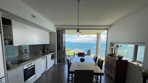 Una cocina moderna con comedor, ventanas amplias y vista al mar.