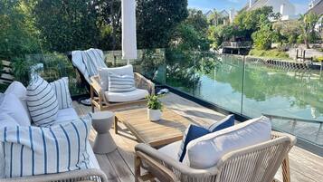 Relax in a serene outdoor space with a clear view of the water, surrounded by lush greenery and comfortable seating.