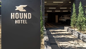 Schild für das Hound Hotel mit modernem Design, einem Parkhaus-Eingang und einem Auto darin.