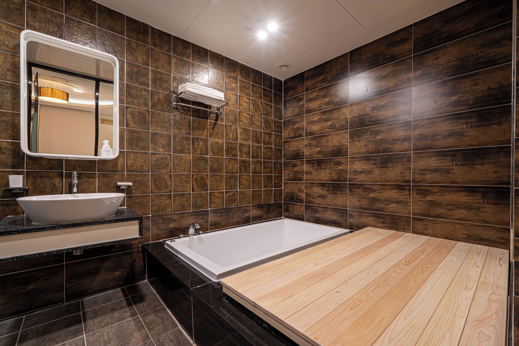 A modern bathroom with a large bathtub, a sink, and a mirror.