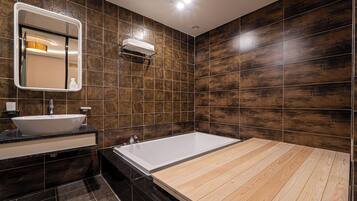 A modern bathroom with a large bathtub, a sink, and a mirror.