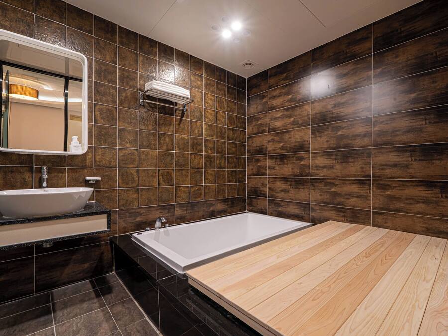 A modern bathroom with a large bathtub, a sink, and a mirror.