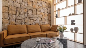 Ein modernes Wohnzimmer mit Steinwand, braunem Sofa, Couchtisch mit Muster und einer Ablage mit Dekoration.