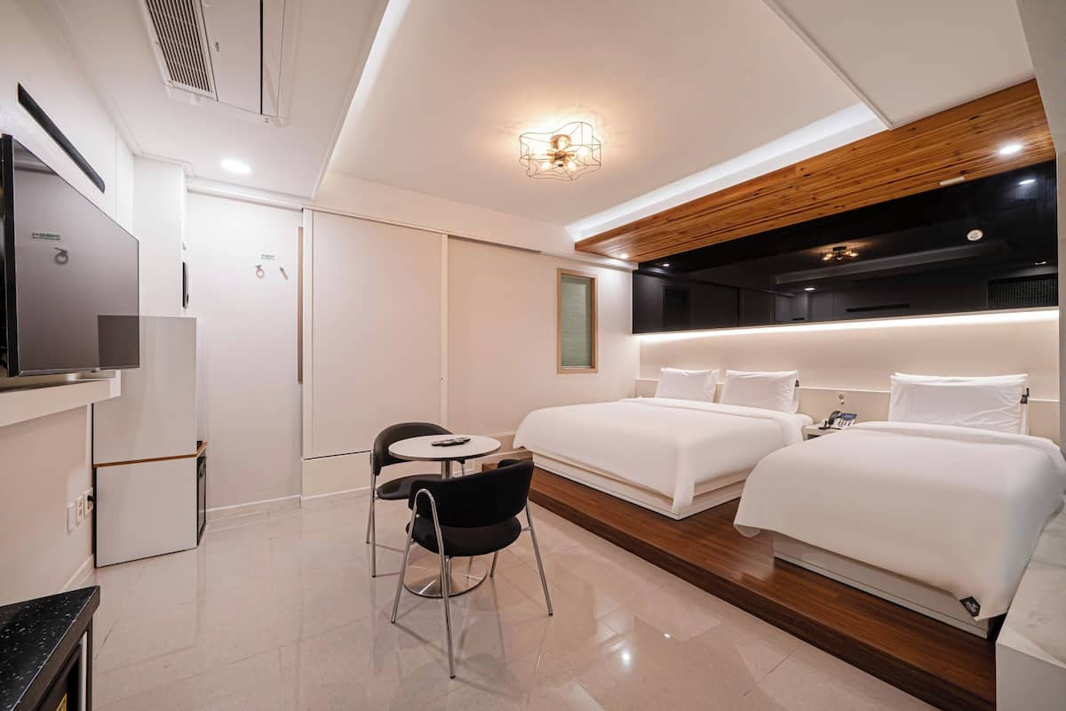 Une chambre d’hôtel moderne équipée d’un lit, de tables de chevet, d’une télévision et d’un bureau avec une chaise.