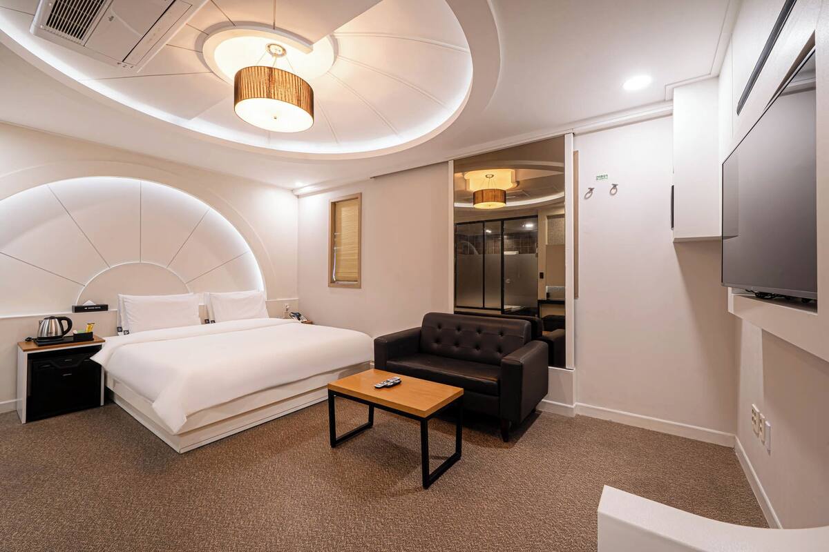 Une chambre d’hôtel moderne équipée d’un lit, d’un canapé, d’une petite table et d’un téléviseur.