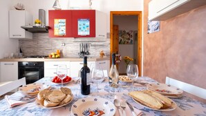 A dining area with a table set for two, featuring plates with a bird design, bread, and a bottle of wine. - Rifugio Al Mare, Ac, Wifi, San Foca (San Foca)