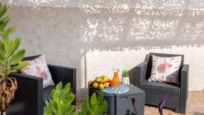 A patio area with two wicker chairs, a small round table with fruits and a drink, and a decorative wall with a lattice pattern. - Rifugio Al Mare, Ac, Wifi, San Foca (San Foca)