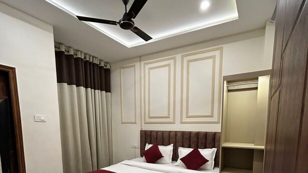 A modern hotel room with a bed, a ceiling fan, a desk, and a wardrobe. - The Commune ISKCON (Varanasi)
