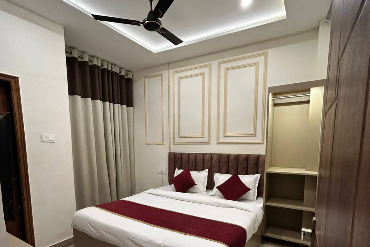 A modern hotel room with a bed, a ceiling fan, a desk, and a wardrobe.
