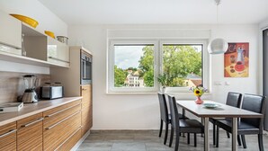 Una cocina moderna con comedor, ventanas amplias y vistas a edificios.