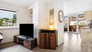 Una sala de estar moderna con televisor de pantalla plana, mueble de madera y un amplio ventanal con vistas a la ciudad.