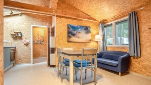 A room with a dining table, chairs, a sofa, a painting, a window with curtains, and a door leading to another room.
