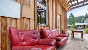 A wooden cabin with a wooden exterior, a whiteboard, and a red leather sofa.