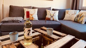 Un salon chaleureux avec un canapé, des coussins décoratifs, une bouteille et une table basse rustique.