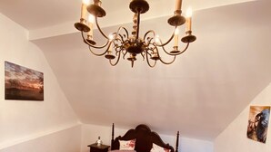 Une chambre à coucher avec un lit à baldaquin, un lustre, un plancher en bois et deux tables de chevet.